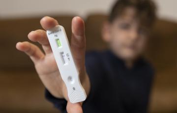 Un niño enseña un test de antígenos