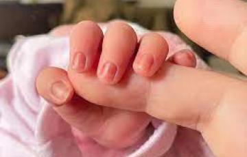 Un bebé recién nacido coge el dedo a su madre