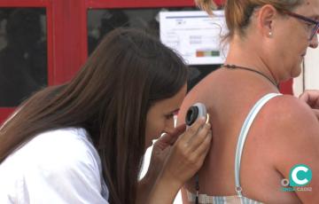 Una especialista realiza un examen visual de manchas y lunares de una usuaria de la playa.