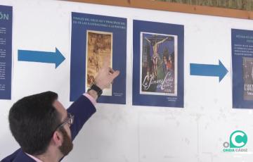 Un guía explica uno de los carteles cofrades que se exponen en la Facultad de Filosofía y Letras hasta el viernes