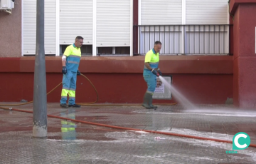 Dos operarios limpian el acerado bajo presión de agua