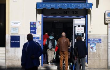 Varias personas hacen cola para comprar décimos de la Lotería de Navidad en Málaga