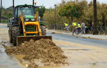 Operarios retiran barro de una carretera en el municipio de Moguer.