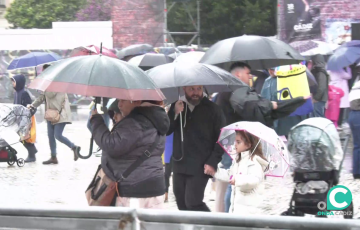 Asistentes a un acto festivo en la plaza de San Antonio intentan protegerse de un inesperado aguacero