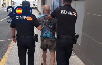 Dos policías escoltan a uno de los detenidos durante la mañana de este martes