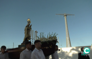 El cortejo durante su recorrido ante la iconíca imagen de una de las gigantéscas torres eléctricas