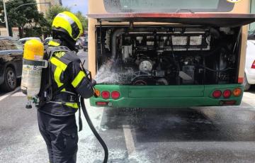 Bomberos sofocan el incendio originado en el motor del autobús urbano. 