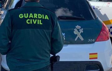 Un agente de la Guardia Civil junto a un vehículo oficial.