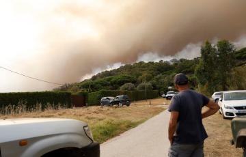 Una persona observa las columnas de humo originadas por el siniestro.
