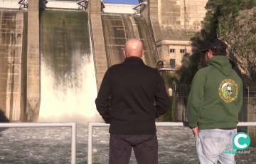 Dos hombres observan el desembalse de agua en el pantano de los Hurones