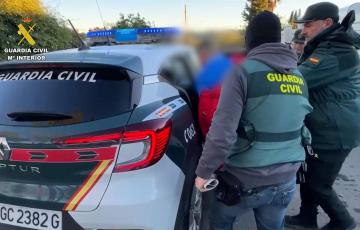 Agentes de la Guardia Civil introducen en el coche a uno de los arrestados