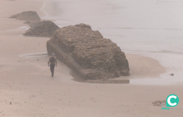 Un hombre pasea junto a uno de los antiguos lienzos sobre la arena