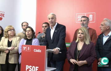 El dirigente del PSOE arropado en su comparecencia por militantes durante la rueda de prensa