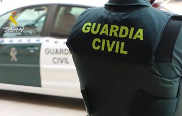 Un agente de la Guardia Civil junto a un vehículo oficial