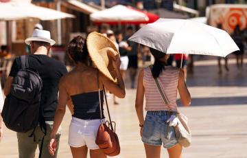 Viandantes se protegen en la calle de las altas temperaturas