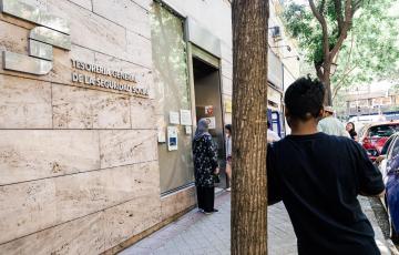 Varias personas esperan en el exterior de una oficina de la Seguridad Social, en el marco de la regularización extraordinaria de migrantes
