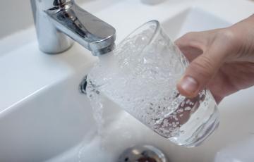 Una persona llena un vaso de agua de un grifo.