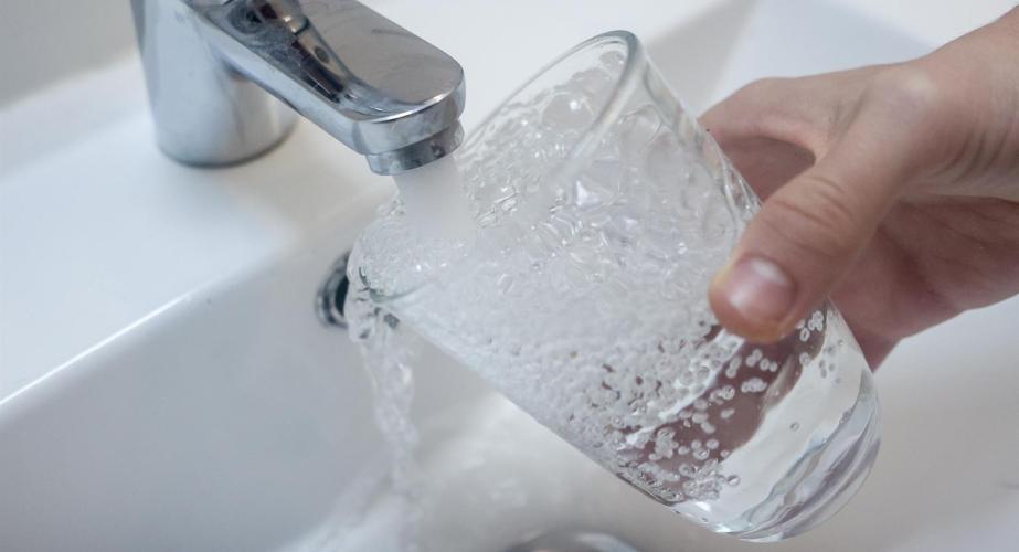 Una persona llena un vaso de agua de un grifo.