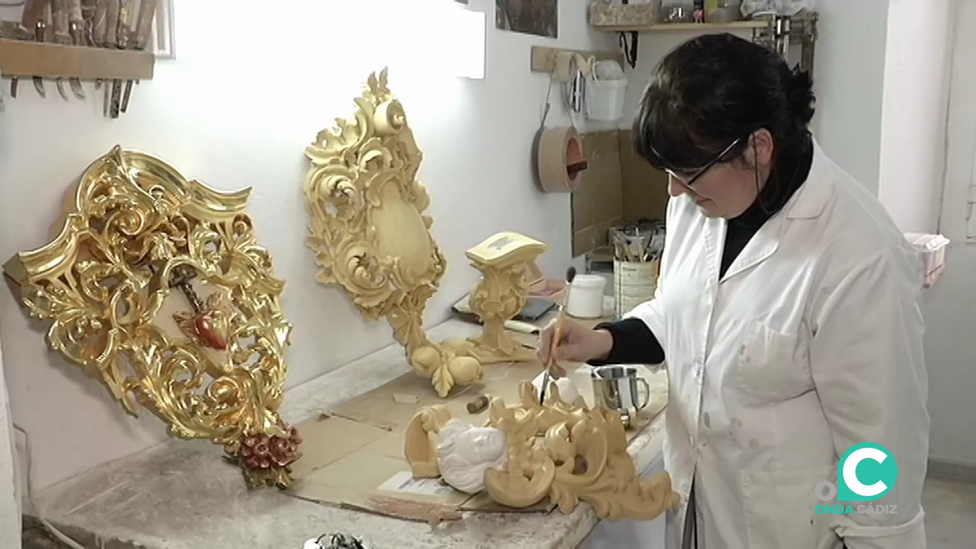 Una trabajadora interviene con un pincel una pieza en un taller de arte sacro.