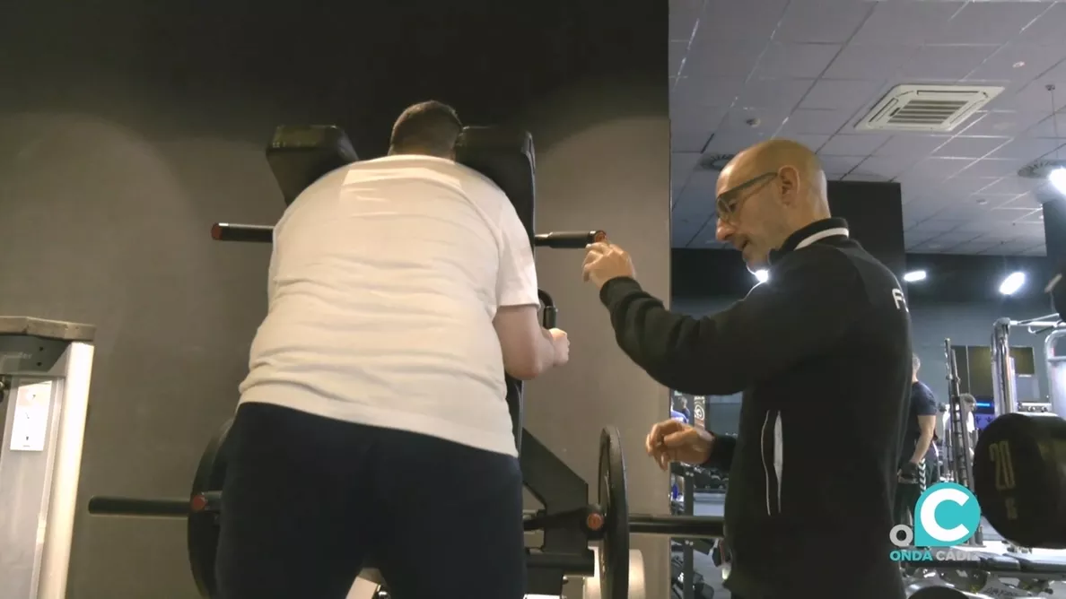 Un monitor de gimnasio imparte instrucciones a un usuario 