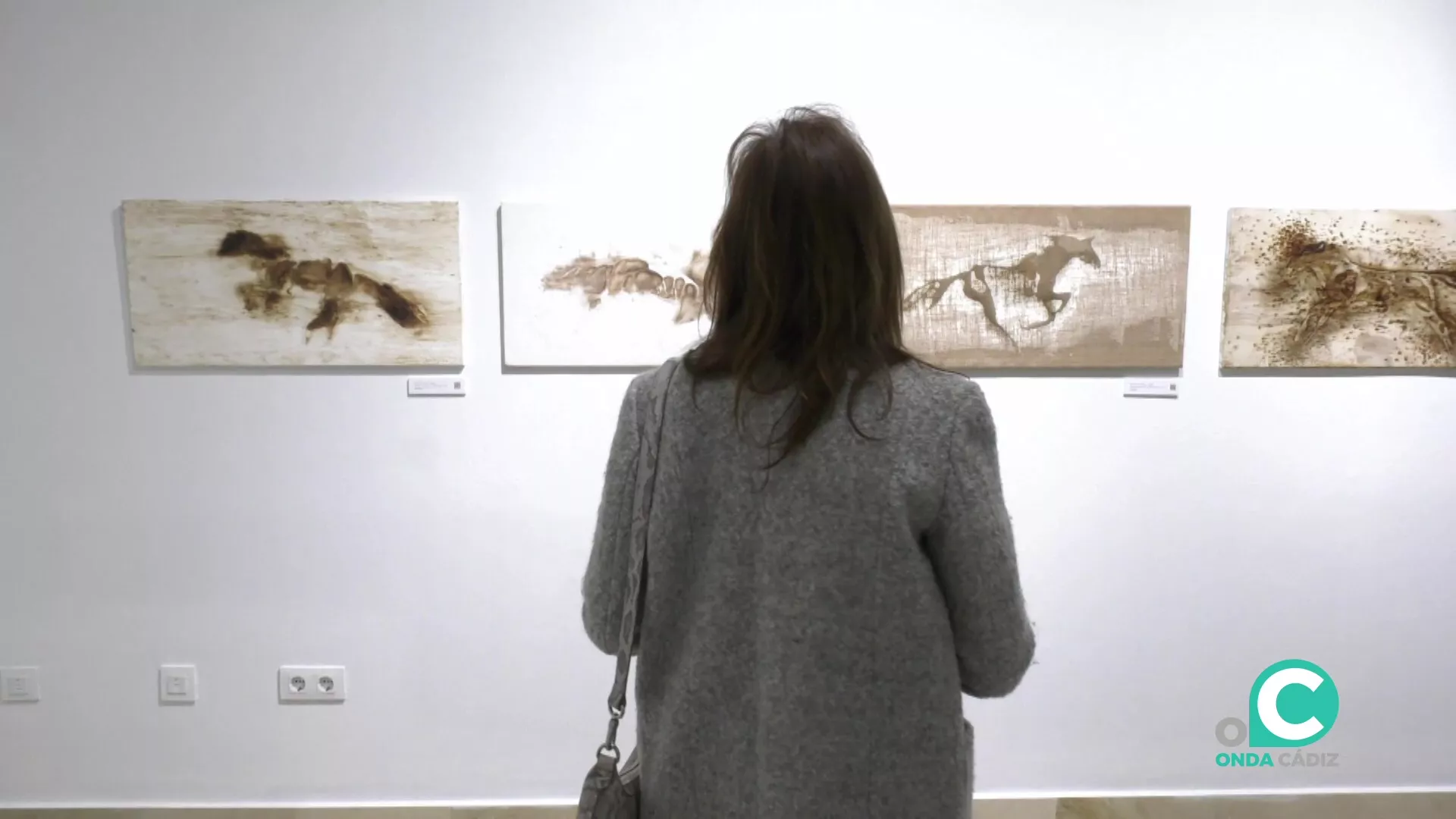 Una visitante contempla varias de las obras de la serie expuestas