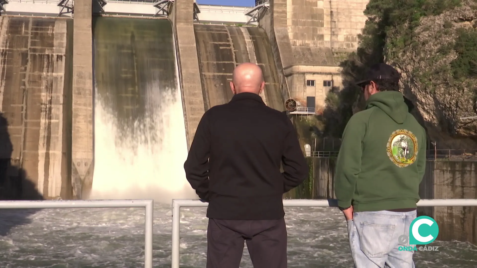 Dos hombres observan el desembalse de agua en el pantano de los Hurones