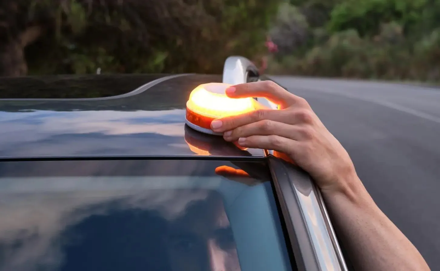 Una persona instala la baliza V16 en la parte alta del vehículo. 