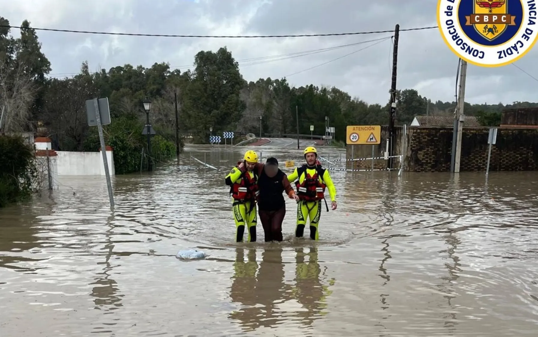 Dos bomberos ayudan a una persona en Arcos a salir de la zona inundada con motivo de la crecida del agua por la apertura de la presa