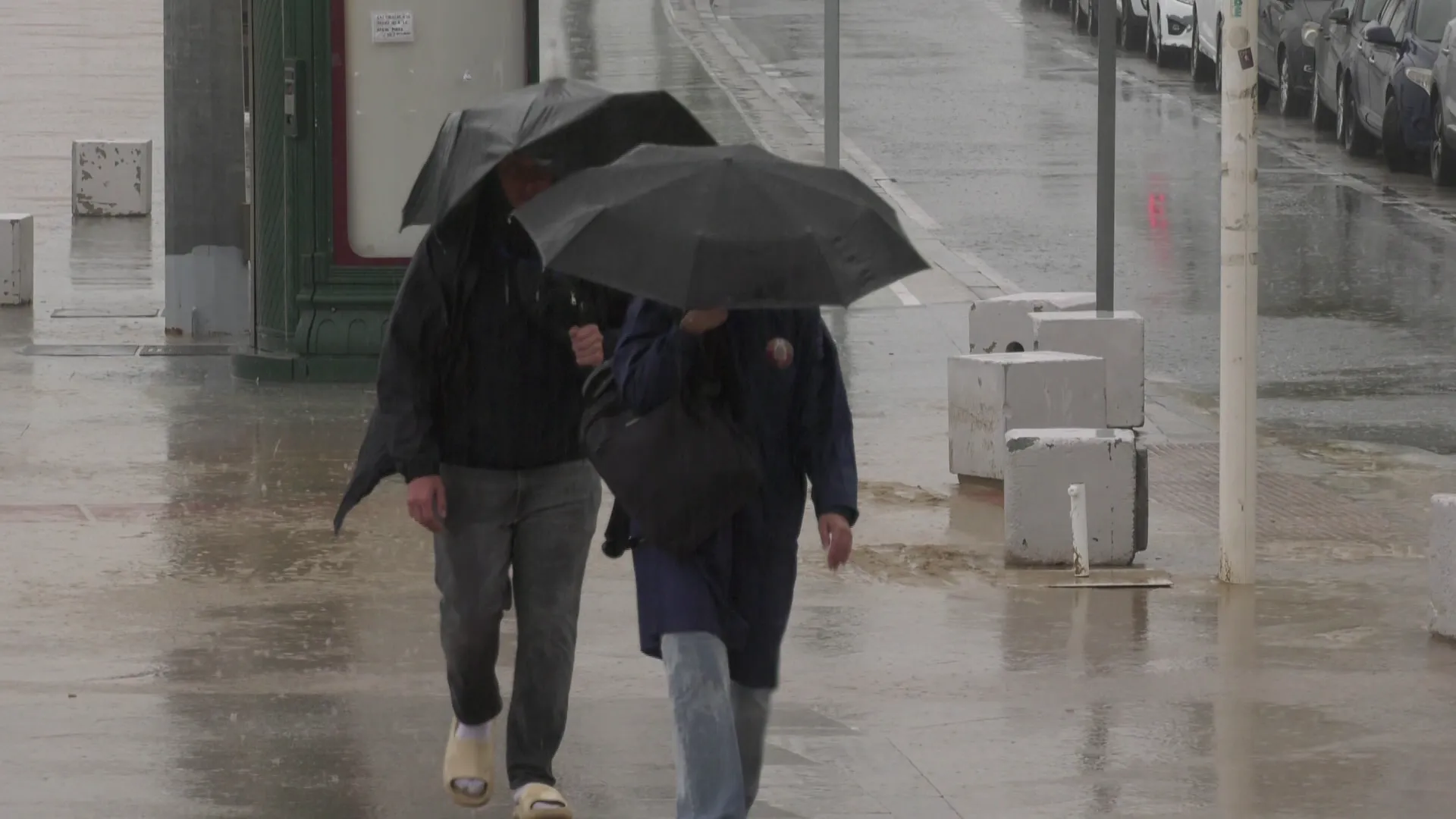 Dos viandantes con paraguas por el Paseo Marítimo de al capital gaditana en una imagen de archivo