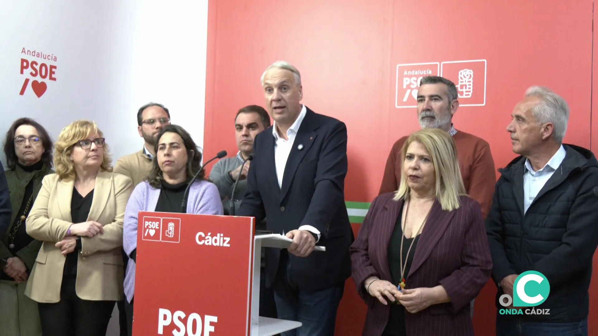 El dirigente del PSOE arropado en su comparecencia por militantes durante la rueda de prensa