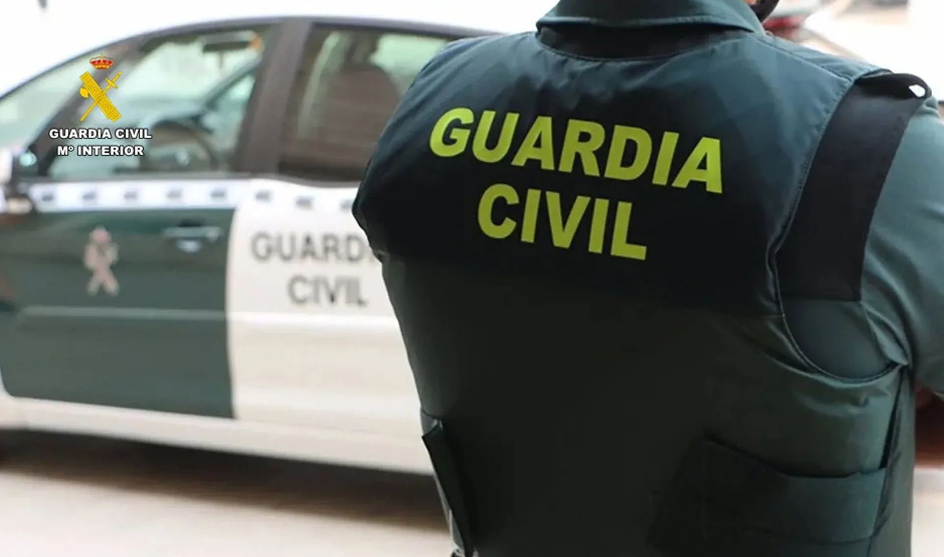 Un agente de la Guardia Civil junto a un vehículo oficial