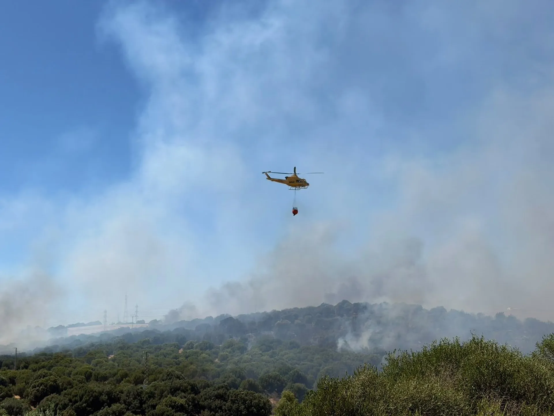 Un helicóptero del Plan Infoca descargando agua sobre el lugar del siniestro